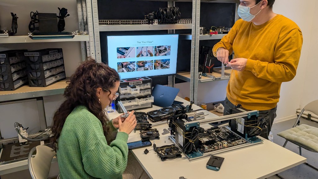Participanți la un atelier de integrare a componentelor de calculator, ghidați pas cu pas de instrucțiuni afișate pe un ecran
